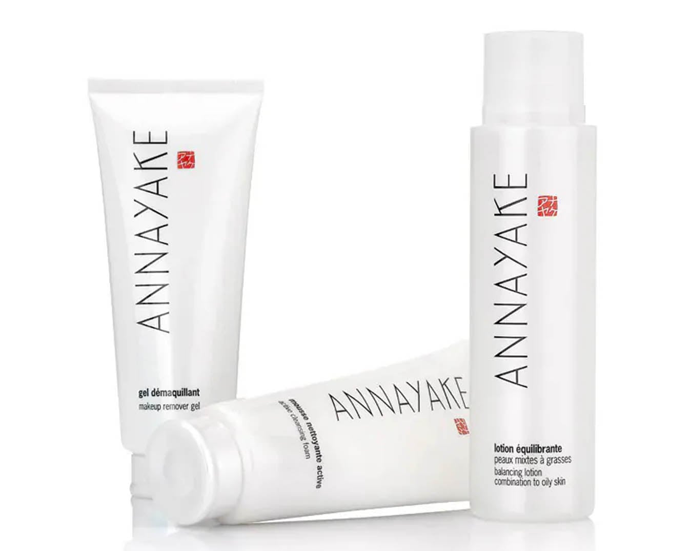 Trzy białe opakowania kosmetyków ANNAYAKE do pielęgnacji skóry: żel do demakijażu, aktywna pianka oczyszczająca i lotion balansujący do cery mieszanej i tłustej.
