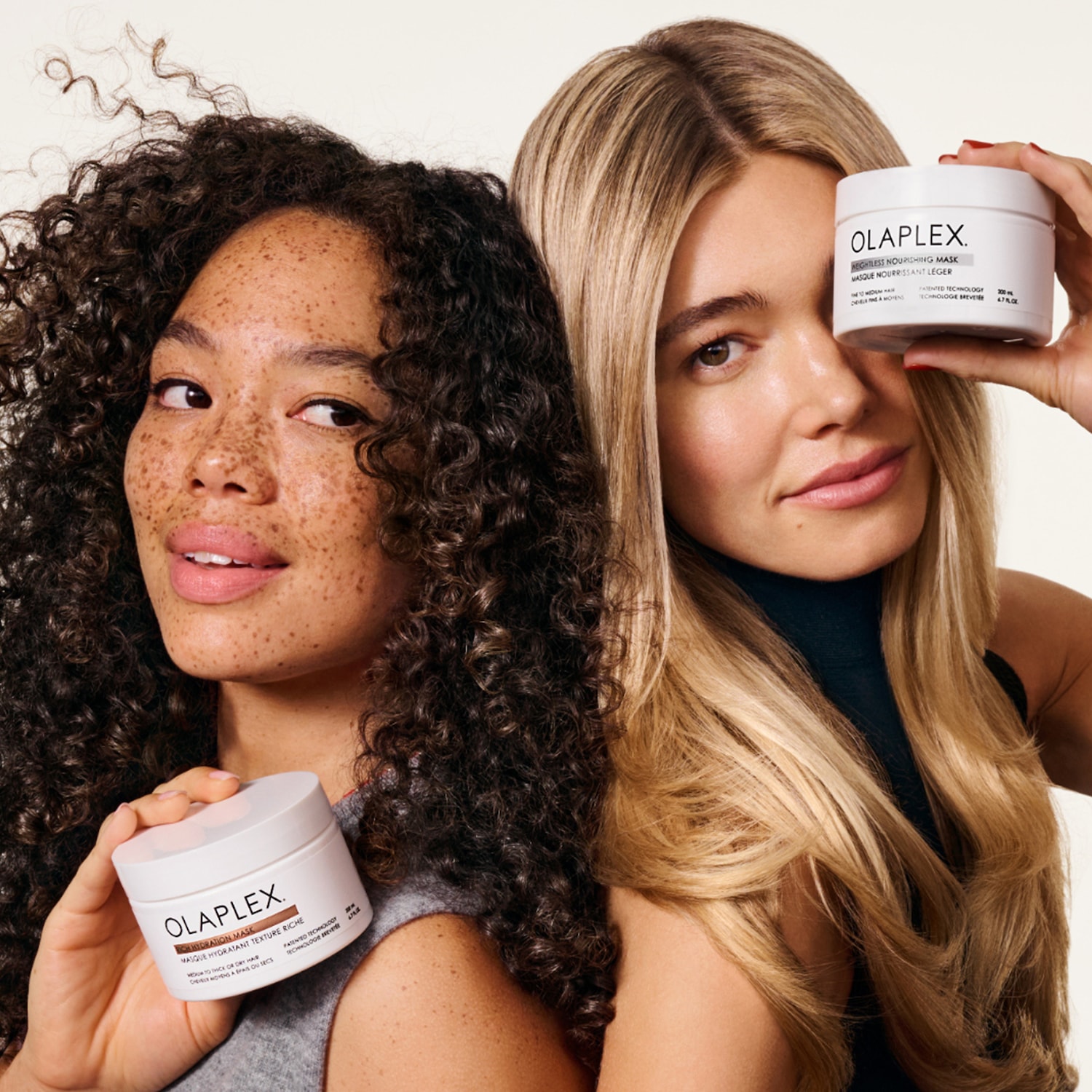Dwie kobiety prezentują maski do włosów Olaplex w białych opakowaniach: Hydration Mask do włosów suchych i Nightless Nourishing Mask do włosów normalnych.