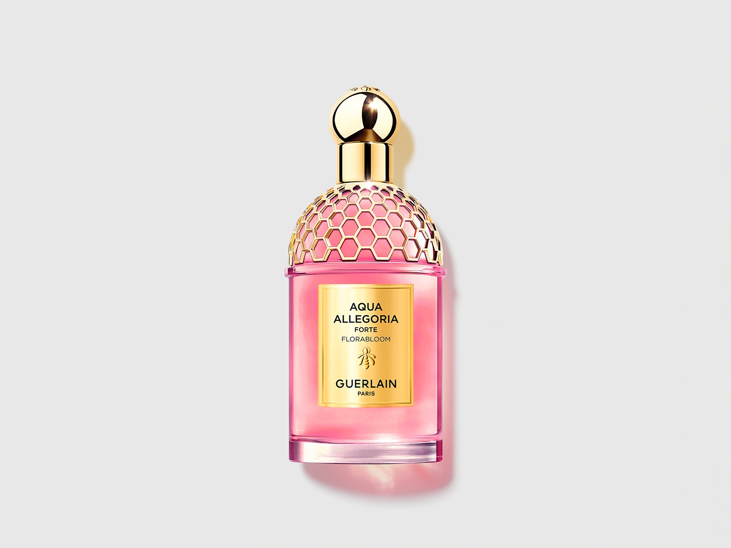 Roze Aqua Allegoria Forte Florabloom parfumfles van Guerlain, met een gouden dop en honingraatmotief.