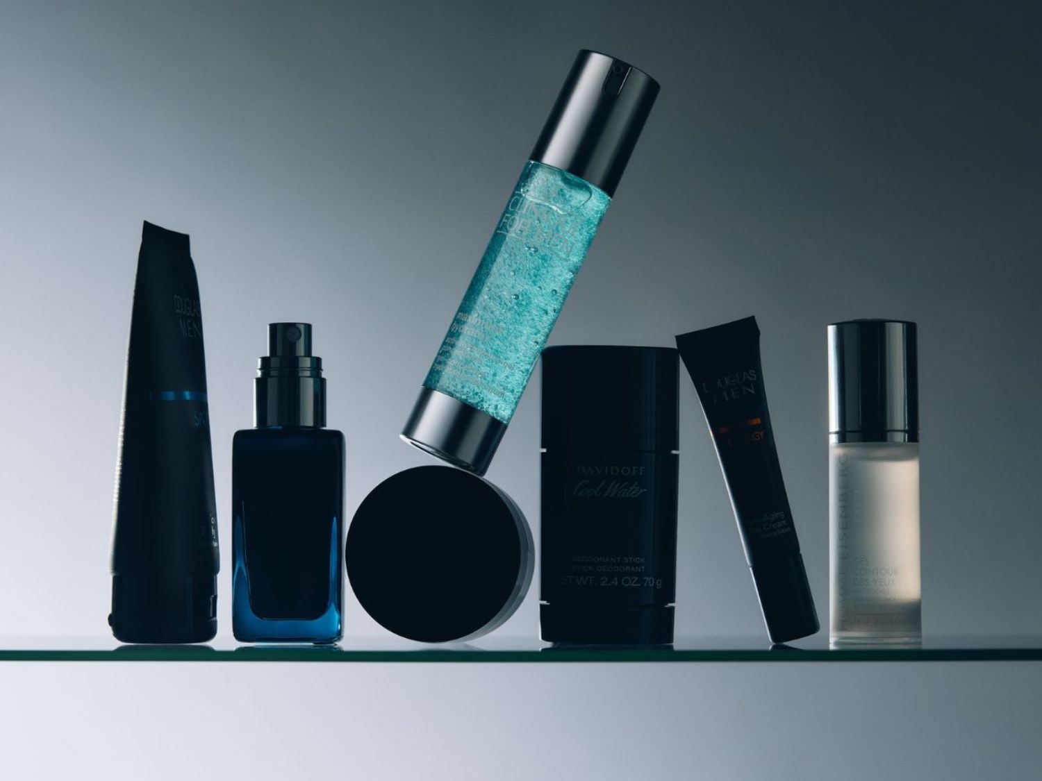 Een verzameling verzorgingsproducten voor mannen, waaronder Douglas Men- en Davidoff Cool Water-deodorant, gepresenteerd in blauwe en zwarte verpakkingen.