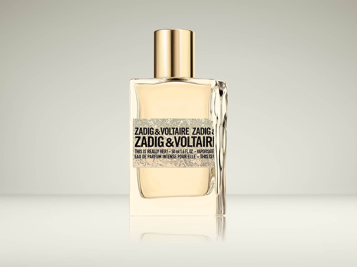 Een heldere glazen flacon van Zadig & Voltaire This is Really Her! Eau de Parfum Intense, met een gouden dop en een zwart-wit etiket.