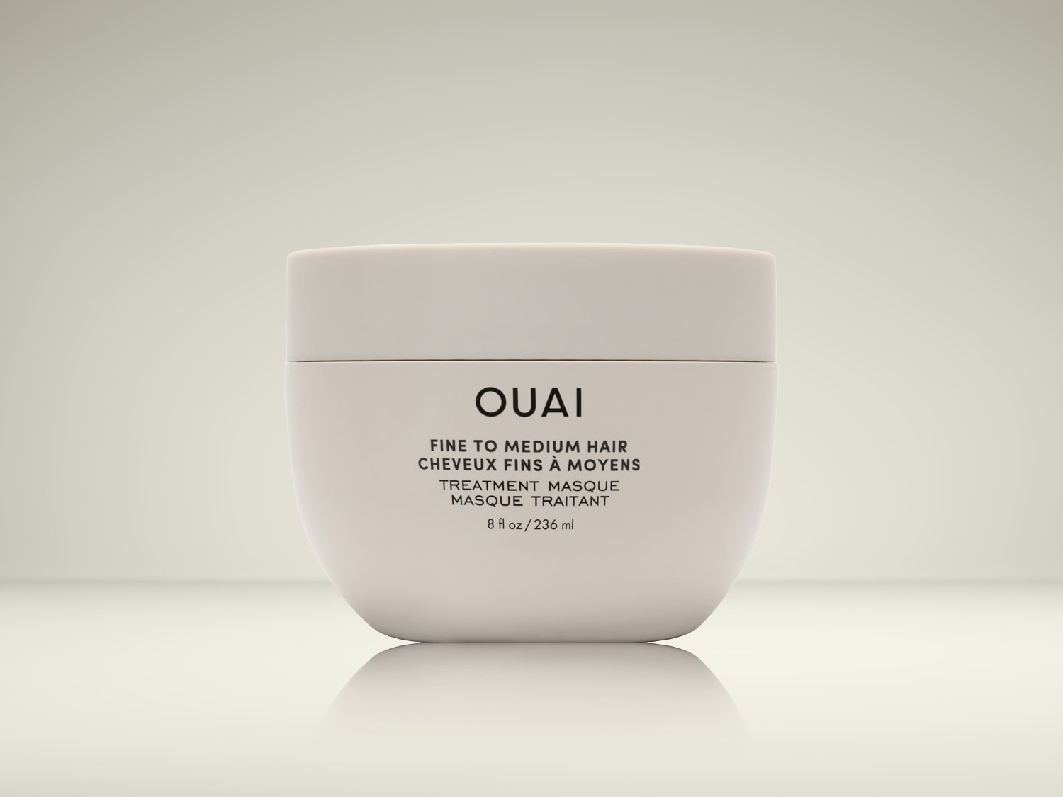 Voici un masque capillaire OUAI pour cheveux fins à moyens, présenté dans un pot blanc épuré de 236 ml.