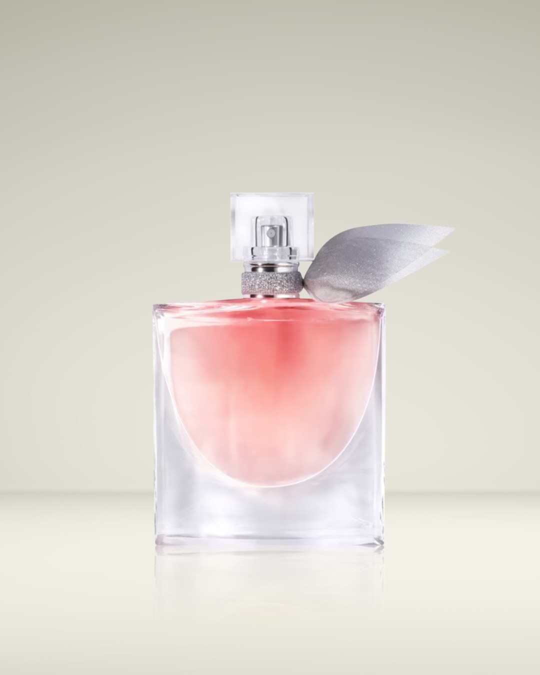 Een elegante parfumfles met een helder glazen vierkant ontwerp, gevuld met een zachtroze vloeistof, versierd met een zilveren lint rond de hals en een transparante dop.
