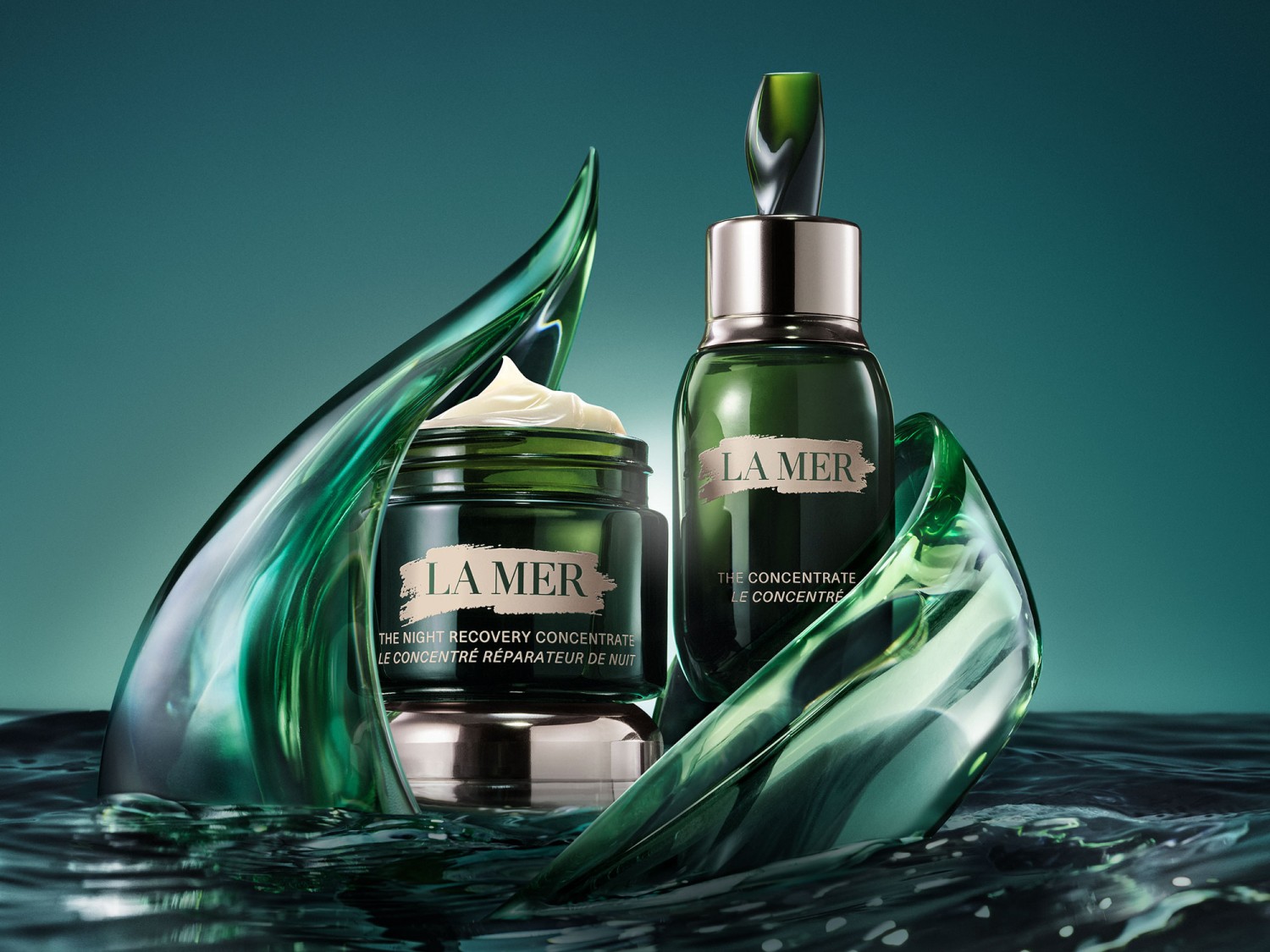 Na tle morskiej zieleni, krem La Mer The Night Recovery Concentrate i serum The Concentrate otoczone abstrakcyjnymi, szklanymi formami, obiecują nocną regenerację i intensywną pielęgnację.