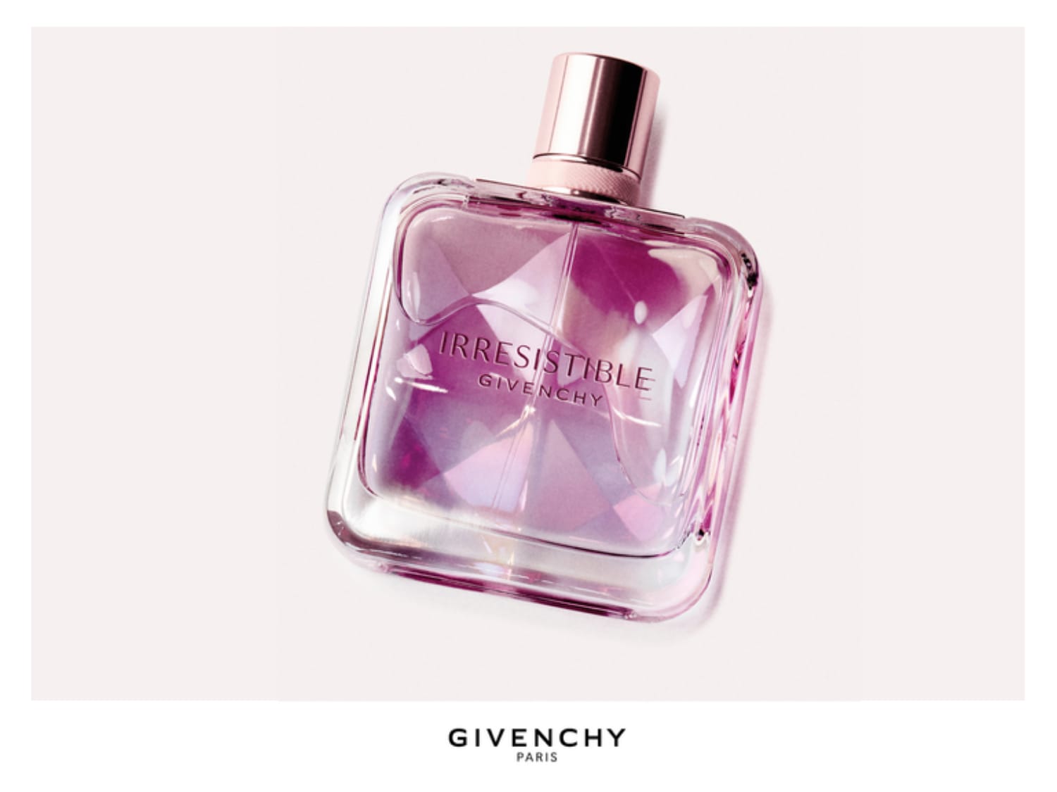 De Irresistible Givenchy Eau de Parfum in een vierkante, glazen fles met roze vloeistof en een roségouden dop, staat schuin op een witte achtergrond.