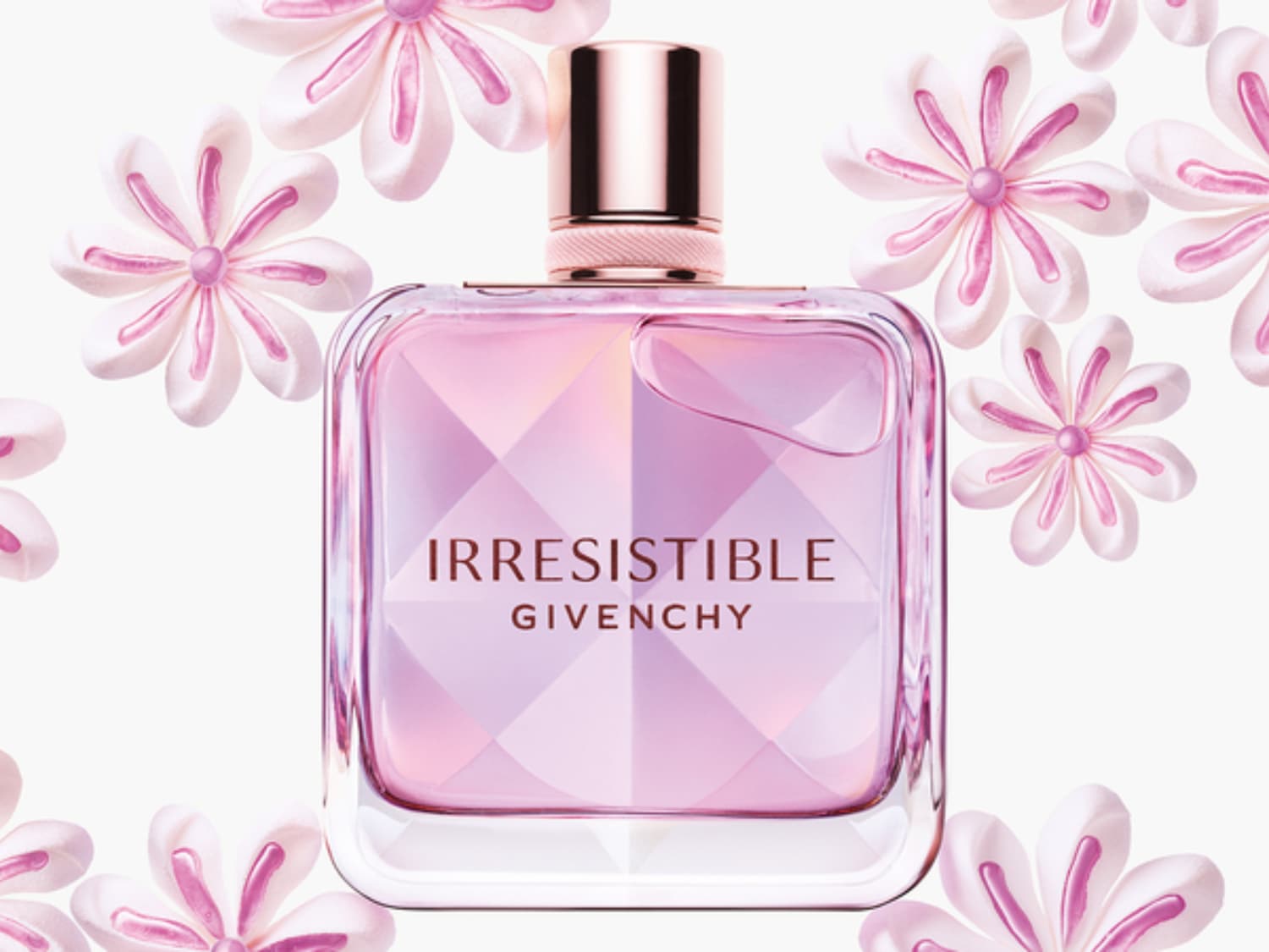 Irresistible Givenchy parfumflesje met roze vloeistof, omringd door witte bloemen met roze accenten.