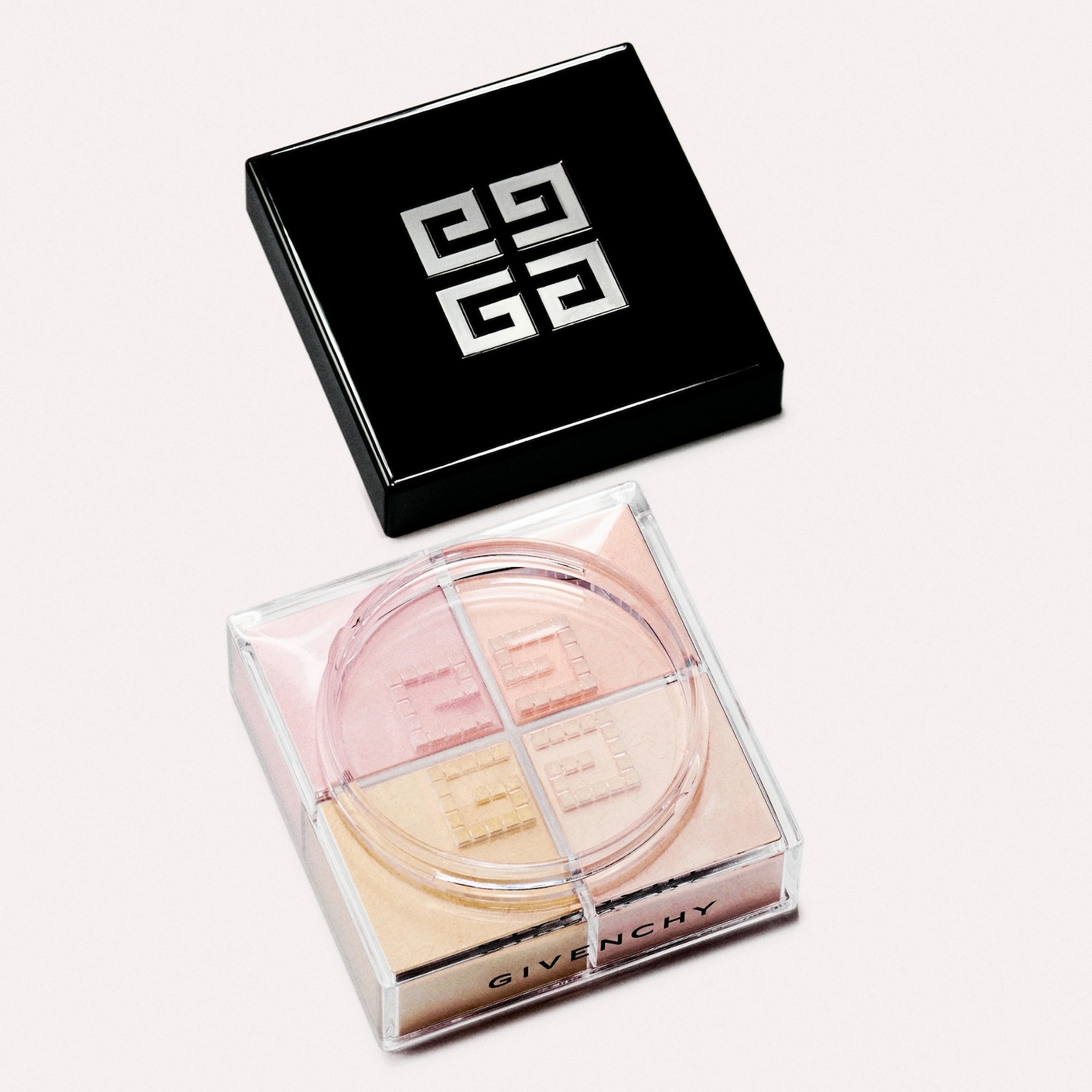 Geopend Givenchy make-up doosje met vier pastelkleurige tinten, roze en geel, met een zwarte deksel met zilver logo.