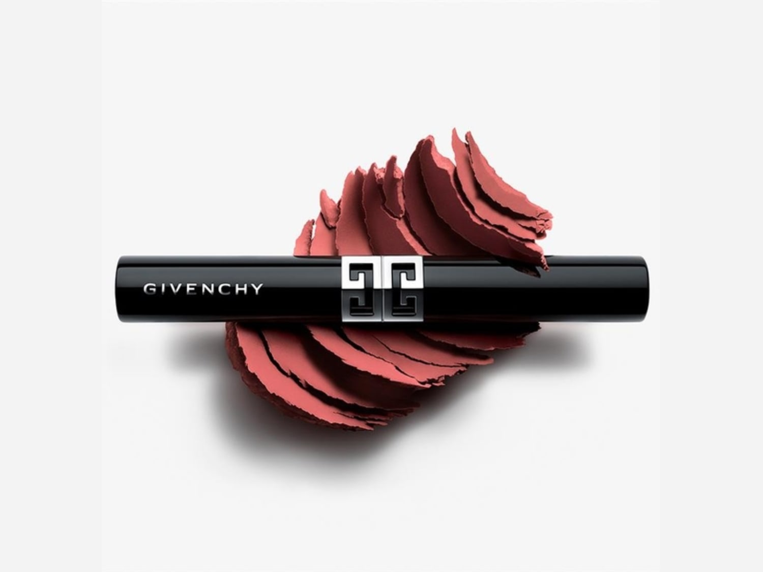 Een zwarte Givenchy lippenstift ligt op een hoopje roze poeder, klaar om je lippen te verwennen met kleur.