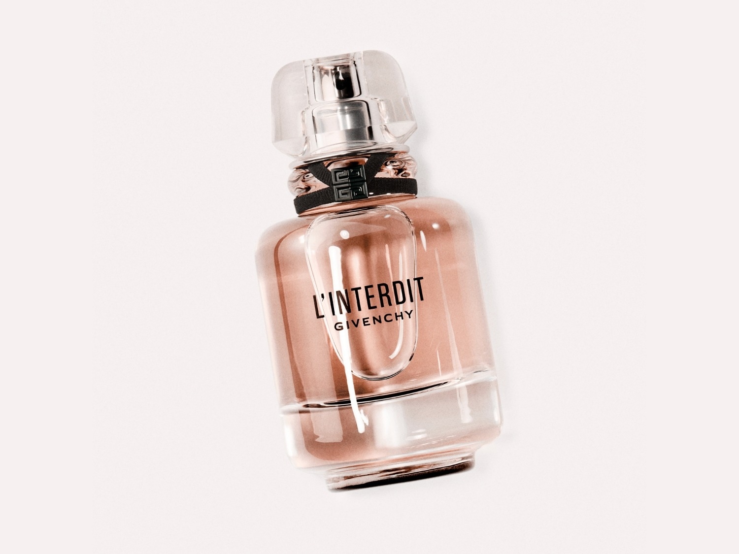 Een flacon Givenchy L'Interdit parfum, met een heldere dop en een zachtroze vloeistof, straalt een subtiele elegantie uit.