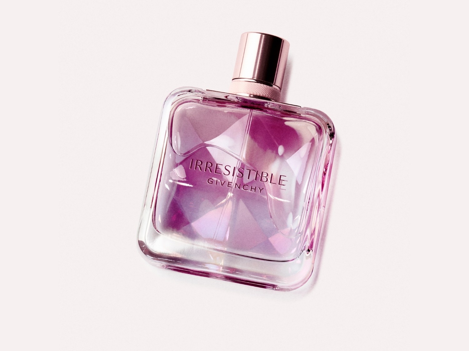 Een vierkante, heldere glazen fles Irresistible Givenchy parfum met een roze dop.