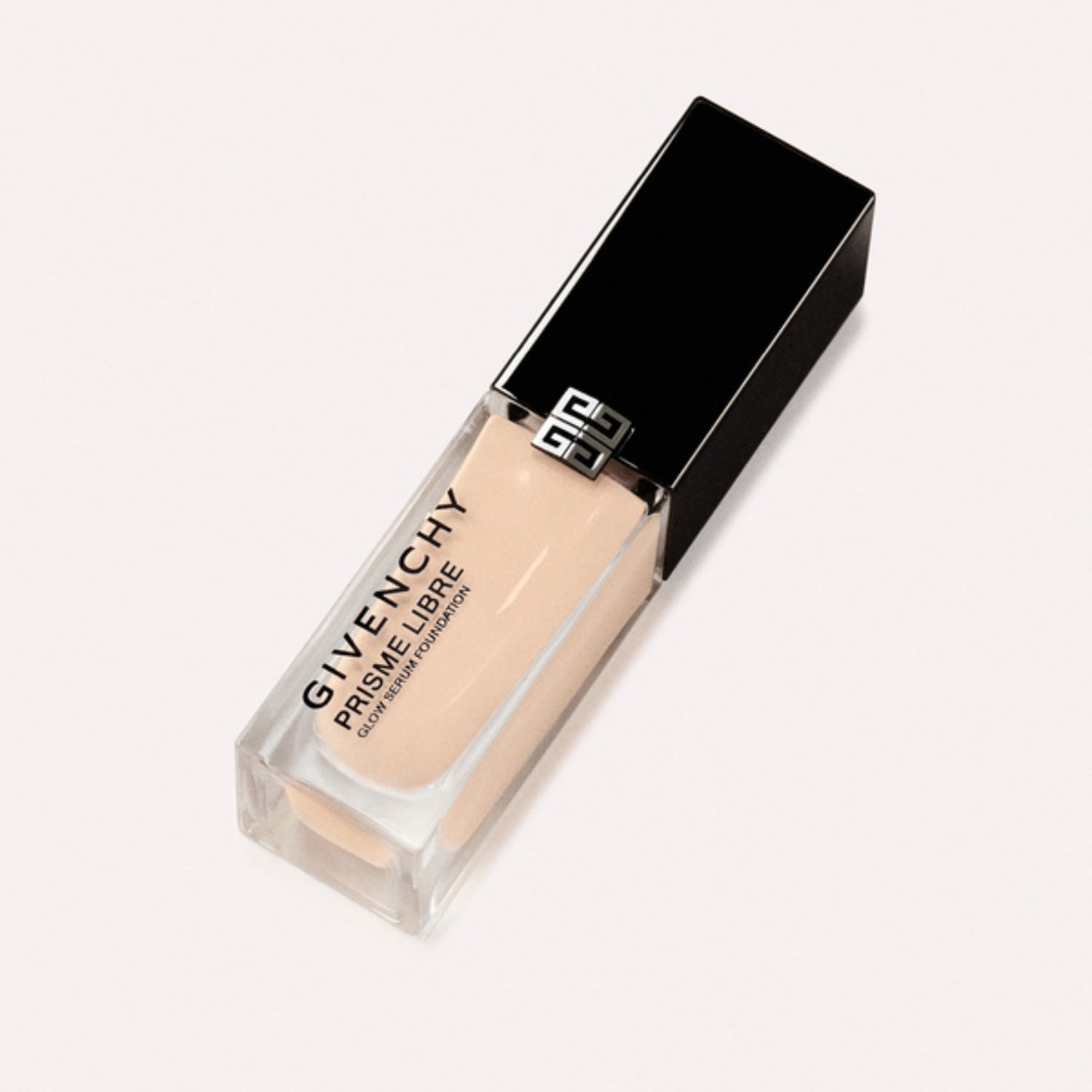 De Givenchy Prisme Libre Glow Serum Foundation in een heldere glazen fles met een zwarte dop, die een zachte, stralende teint belooft.