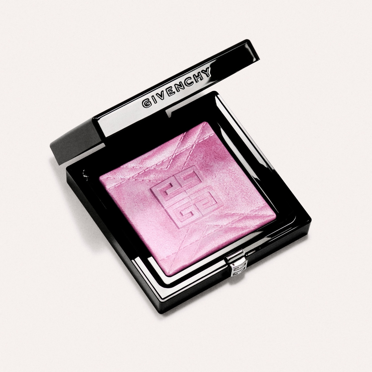 Open compact van Givenchy met een glinsterende, lichtroze highlighter, verpakt in een zwarte, vierkante doos met het Givenchy-logo in reliëf.