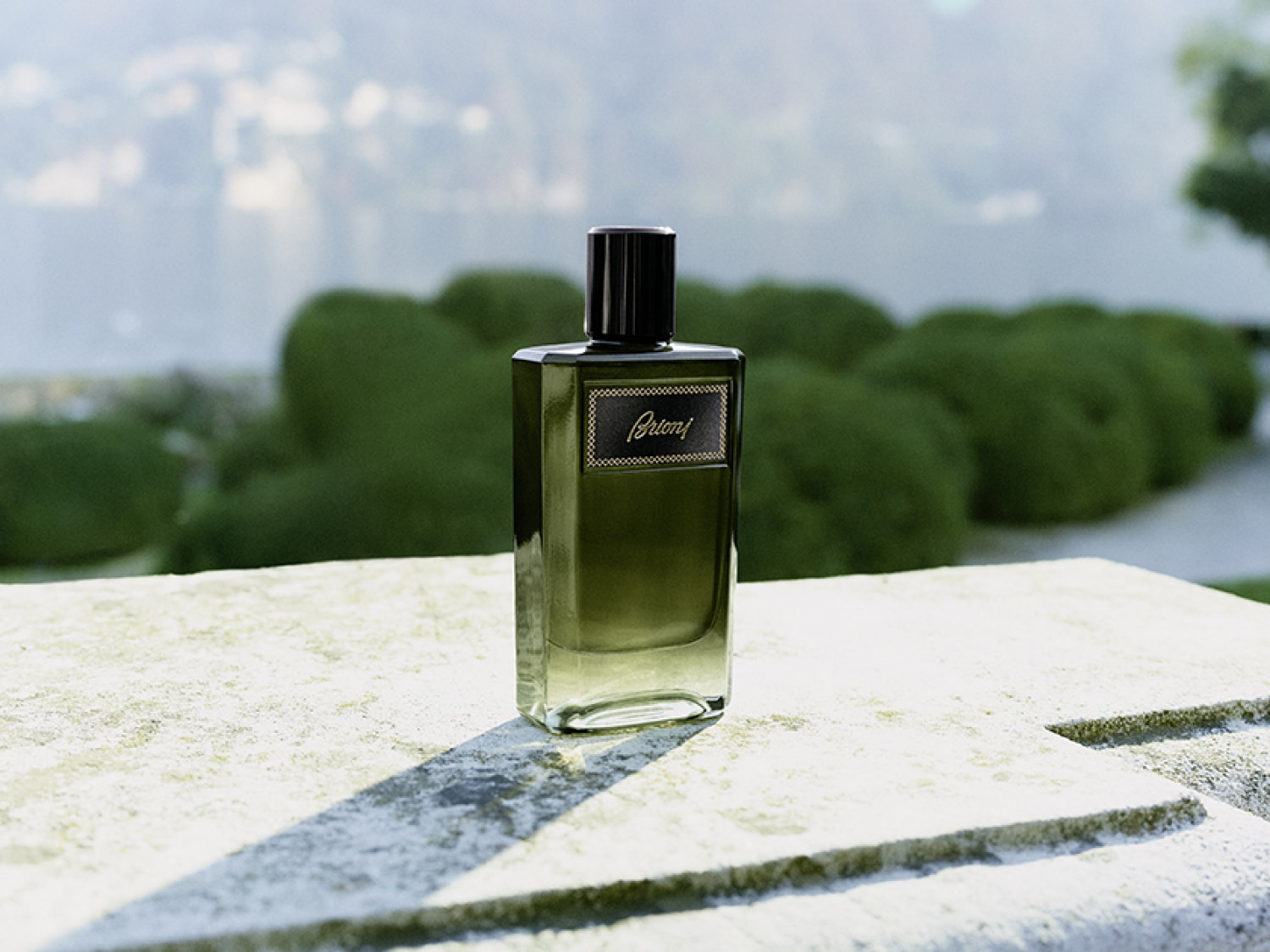 Butelka perfum Brioni o pojemności 100 ml ma elegancki, prostokątny kształt i jest wykonana z zielonego szkła, które stopniowo przechodzi w przezroczystość u podstawy.