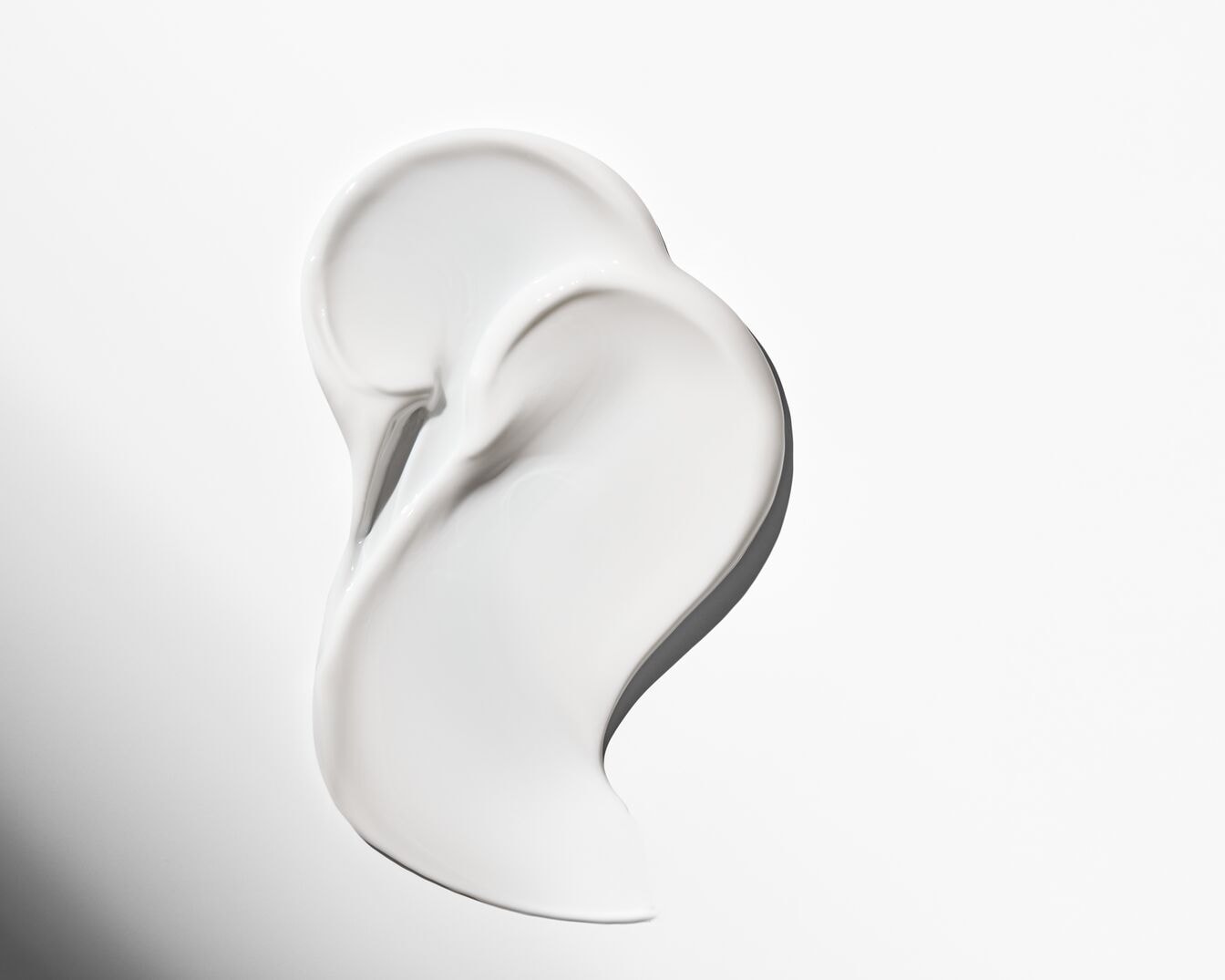 Nahaufnahme eines Klecks weißer, glänzender Creme, die eine weiche und geschmeidige Textur suggeriert.