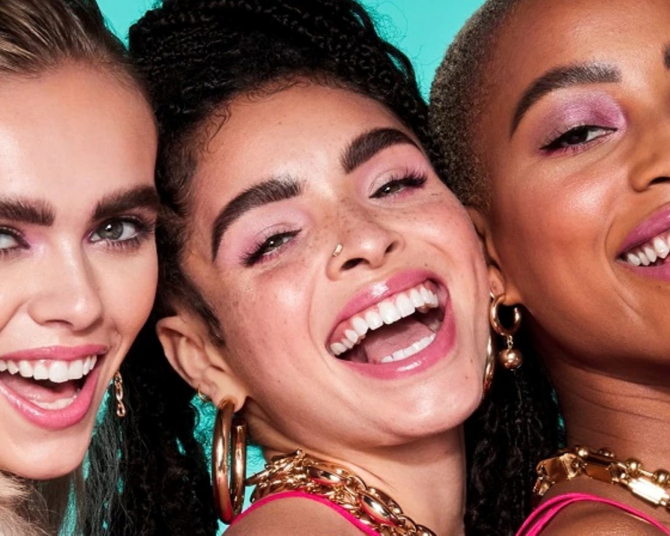 Nahaufnahme von drei strahlenden Frauen mit rosa Lidschatten und glänzenden Lippen, die goldene Accessoires tragen.