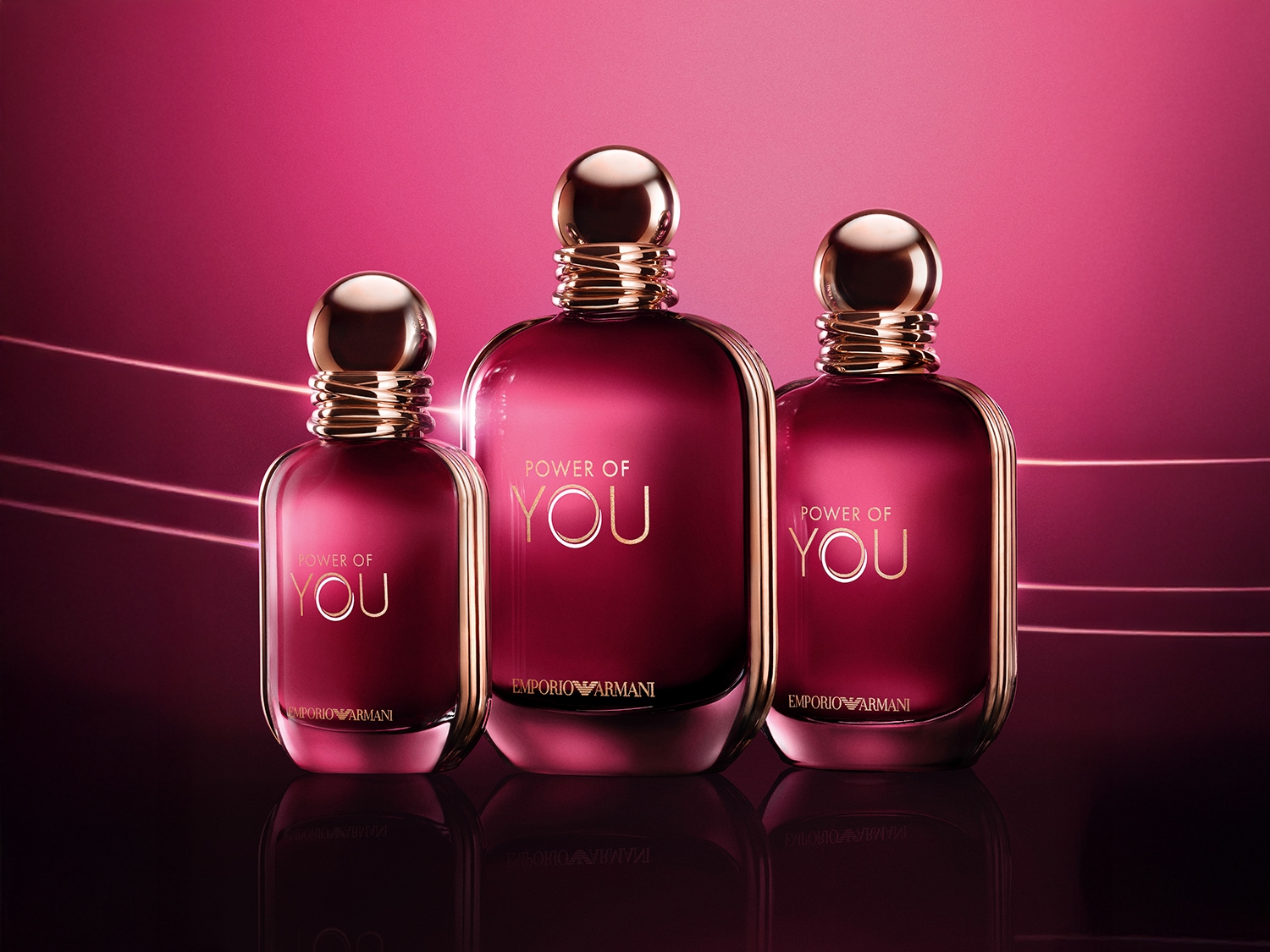 Trzy flakony perfum Emporio Armani Power of You w odcieniach czerwieni i złota, ustawione obok siebie na błyszczącej powierzchni.