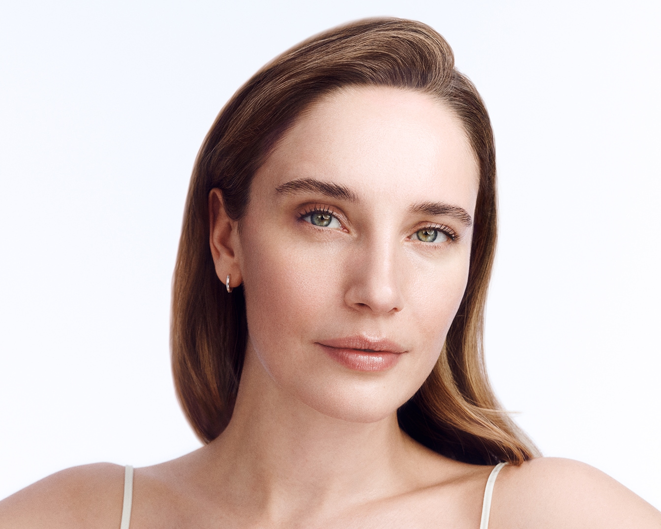 Portret kobiety o jasnej karnacji, z zielonymi oczami i brązowymi włosami, spoglądającej wprost, z delikatnym uśmiechem.