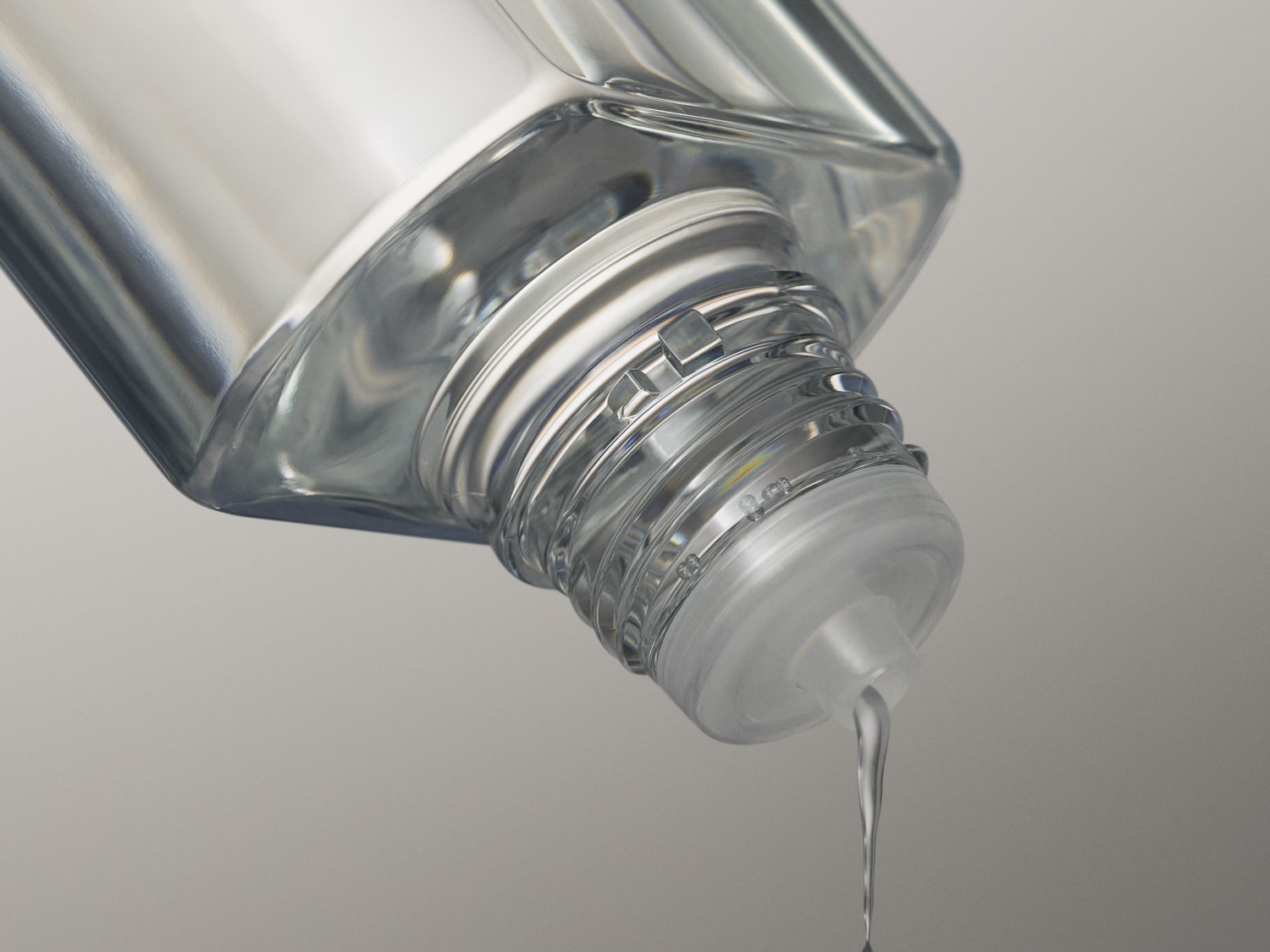 Klares Gesichtswasser fließt aus einer durchsichtigen Flasche.