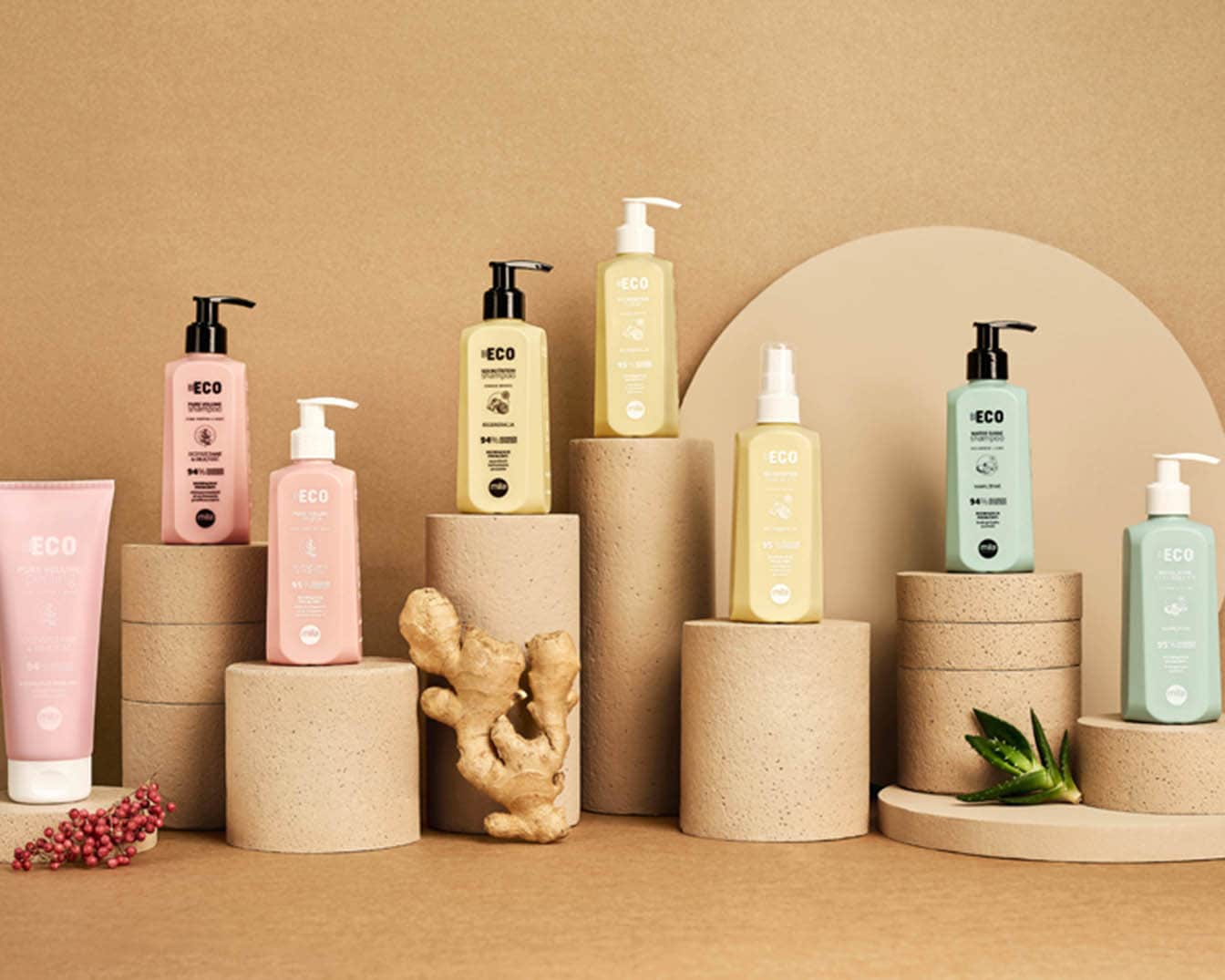 Różnokolorowe butelki i tubki produktów ECO do pielęgnacji włosów i ciała, ustawione na cylindrycznych postumentach, tworzą naturalną i ekologiczną kompozycję.