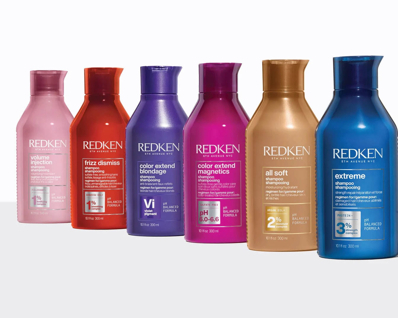 Różnokolorowe butelki szamponów Redken 5th Avenue NYC, w tym Volume Injection w różowym opakowaniu, Frizz Dismiss w czerwonym, Color Extend Blondage w fioletowym, Color Extend Magnetics w różowym, All Soft w złotym i Extreme w niebieskim.