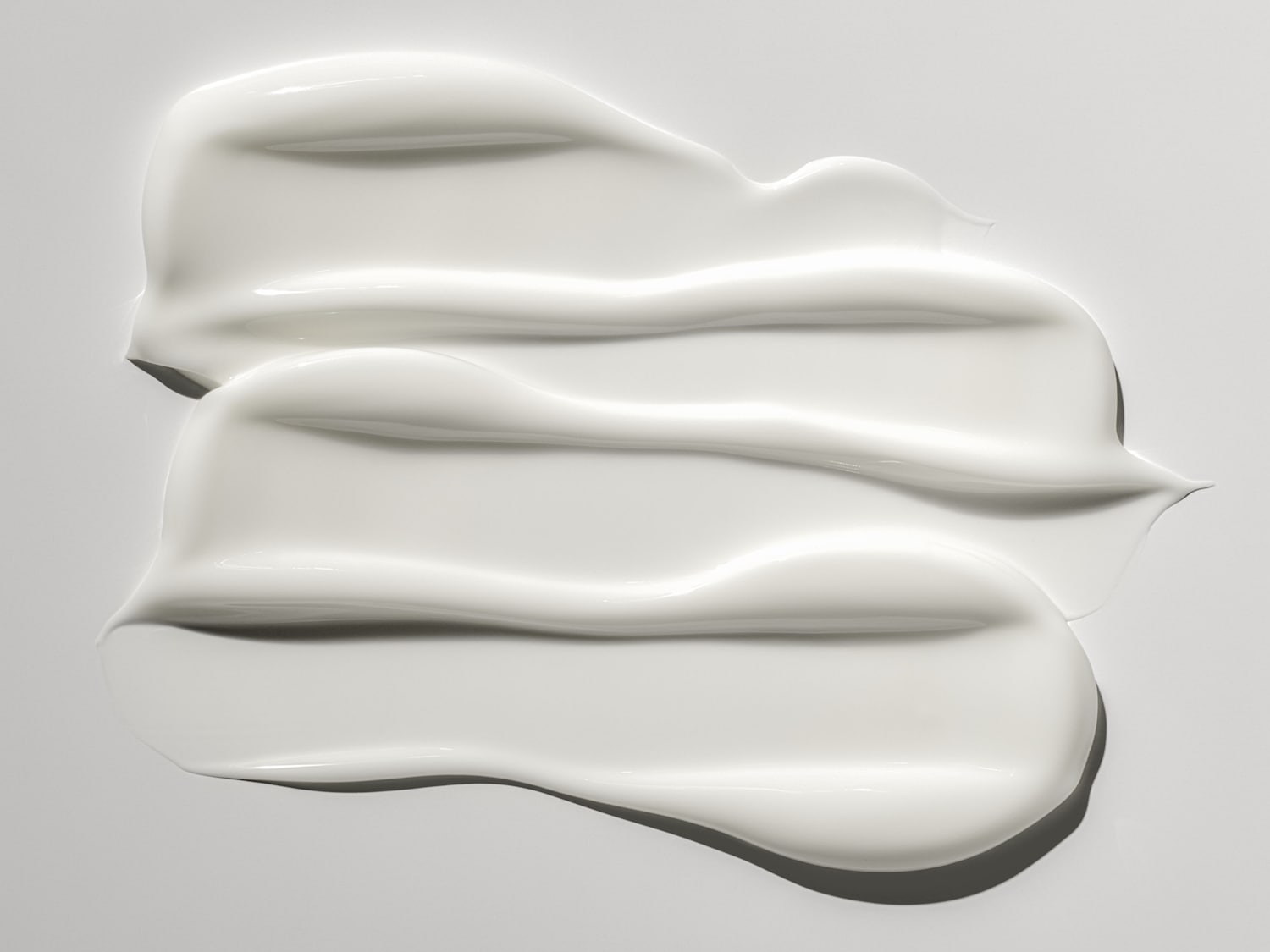 Nahaufnahme von drei glänzenden, weißen Creme Klecksen, die eine reichhaltige Textur und Feuchtigkeitspflege suggerieren.