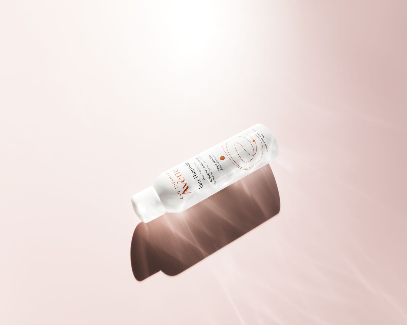 Das Avène Thermalwasserspray in einer weißen Sprühflasche mit orangefarbenen Akzenten, die für seine beruhigenden und reizlindernden Eigenschaften für empfindliche Haut wirbt.