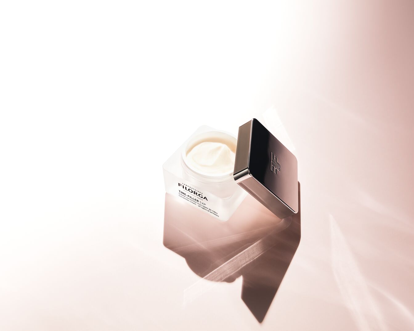 Die Filorga Time-Filler 5XP Creme in einem durchsichtigen Tiegel mit einer schwarzen Kappe daneben, die das Markenlogo zeigt, verspricht eine umfassende Faltenkorrektur.