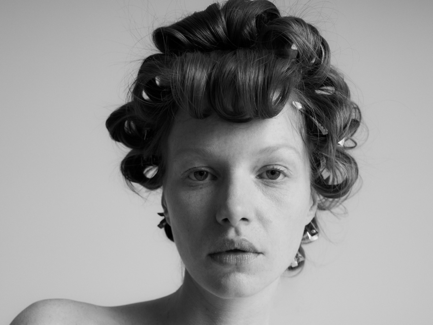 Schwarz-Weiß-Porträt einer Frau mit Lockenwicklern im Haar, die einen klassischen und vorbereitenden Look für das Haarstyling zeigt.