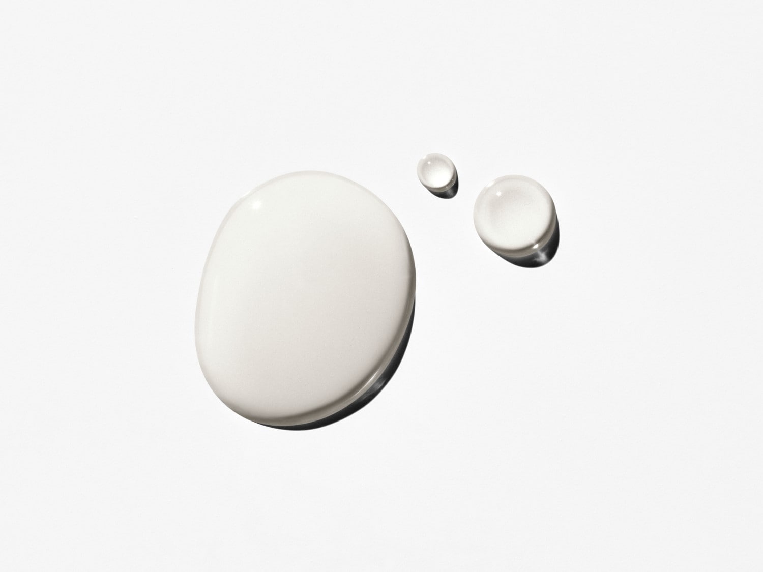 Gotas de crema blanca sobre una superficie clara, mostrando la textura suave e hidratante del producto.