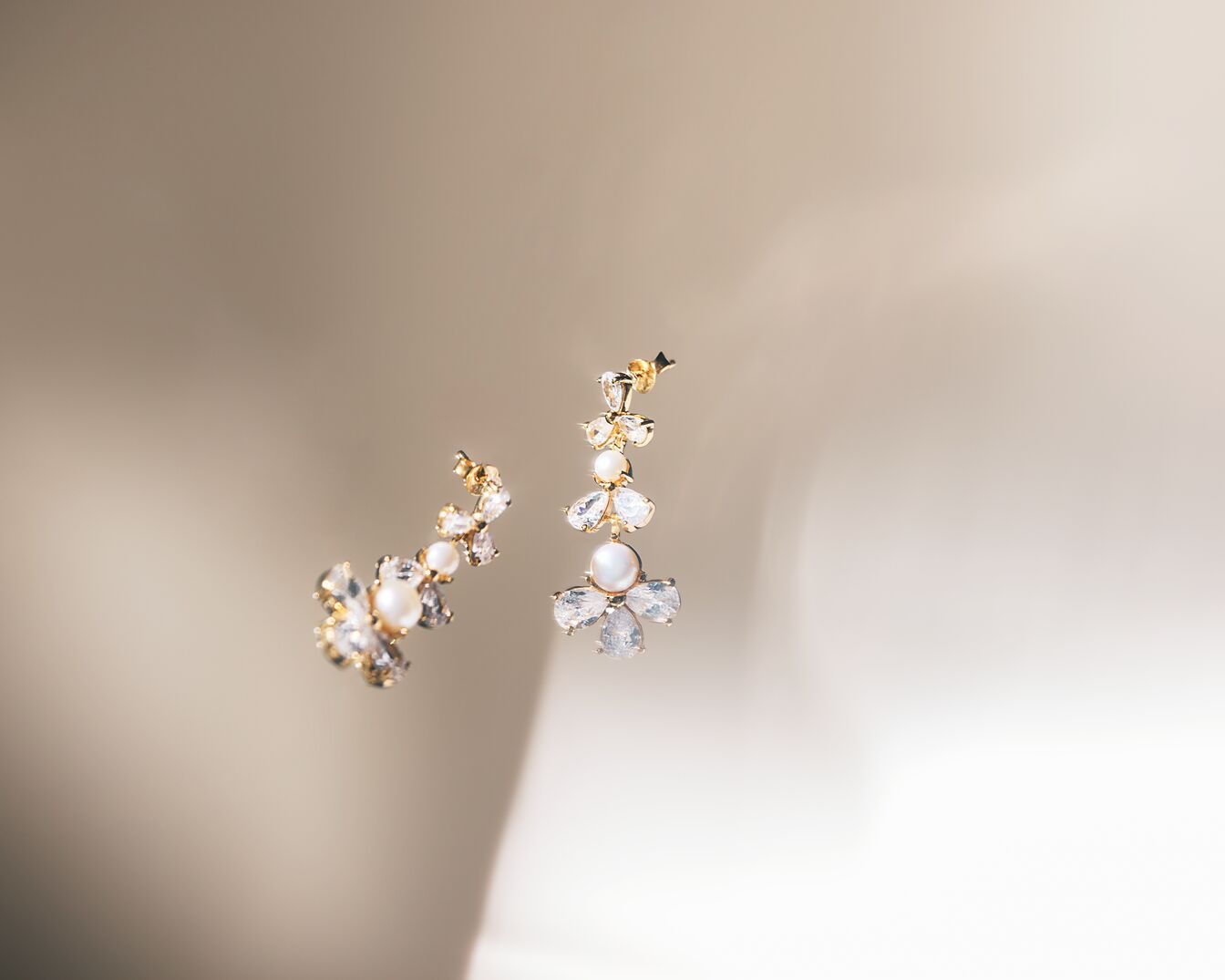 Elegante Ohrringe mit goldenen Fassungen, verziert mit schimmernden Kristallen und zarten Perlen, die einen Hauch von Luxus und Raffinesse ausstrahlen.