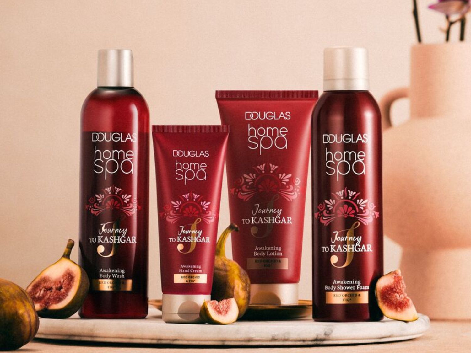 Vier roodkleurige Douglas Home Spa producten uit de Journey to Kashgar lijn, waaronder body wash, handcrème, bodylotion en body shower foam, verrijkt met rode orchidee en vijg.