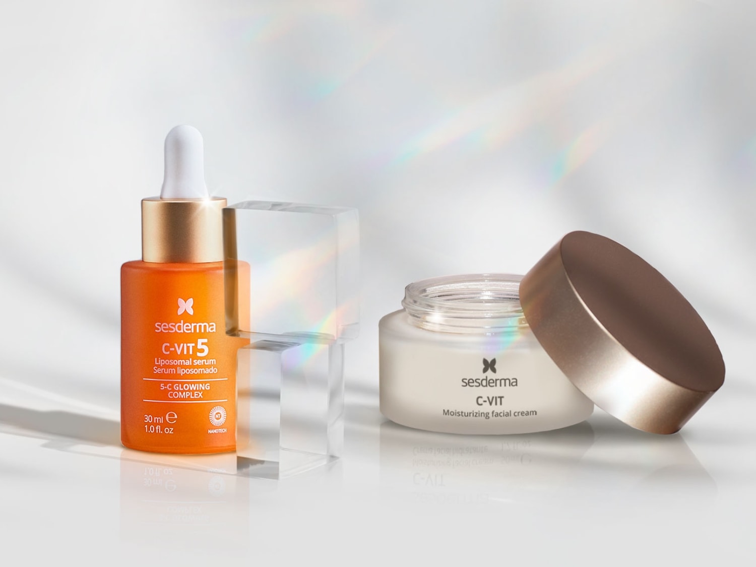 Pomarańczowe serum liposomowe Sesderma C-Vit 5 z kompleksem rozświetlającym 5-C i krem nawilżający do twarzy C-Vit w białym słoiczku z otwartą nakrętką.