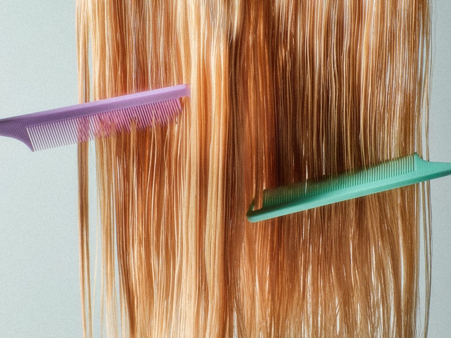 Capelli lunghi e lisci, di colore biondo e castano chiaro, sono pettinati da due pettini, uno viola e uno verde acqua, che scorrono tra le ciocche.