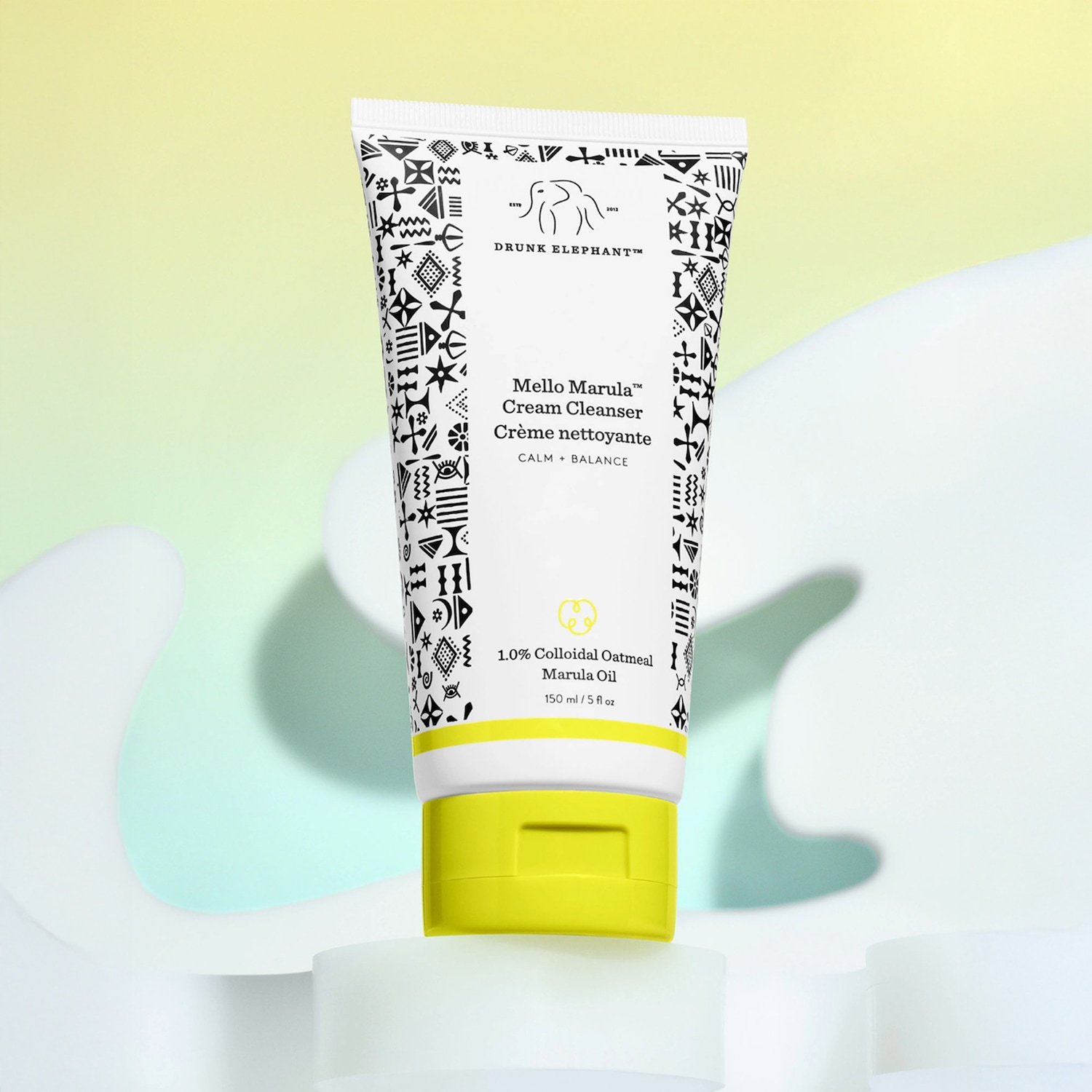 Drunk Elephant Mello Marula Cream Cleanser in een witte tube met zwarte patronen en een gele dop, voor een kalme en evenwichtige reiniging.