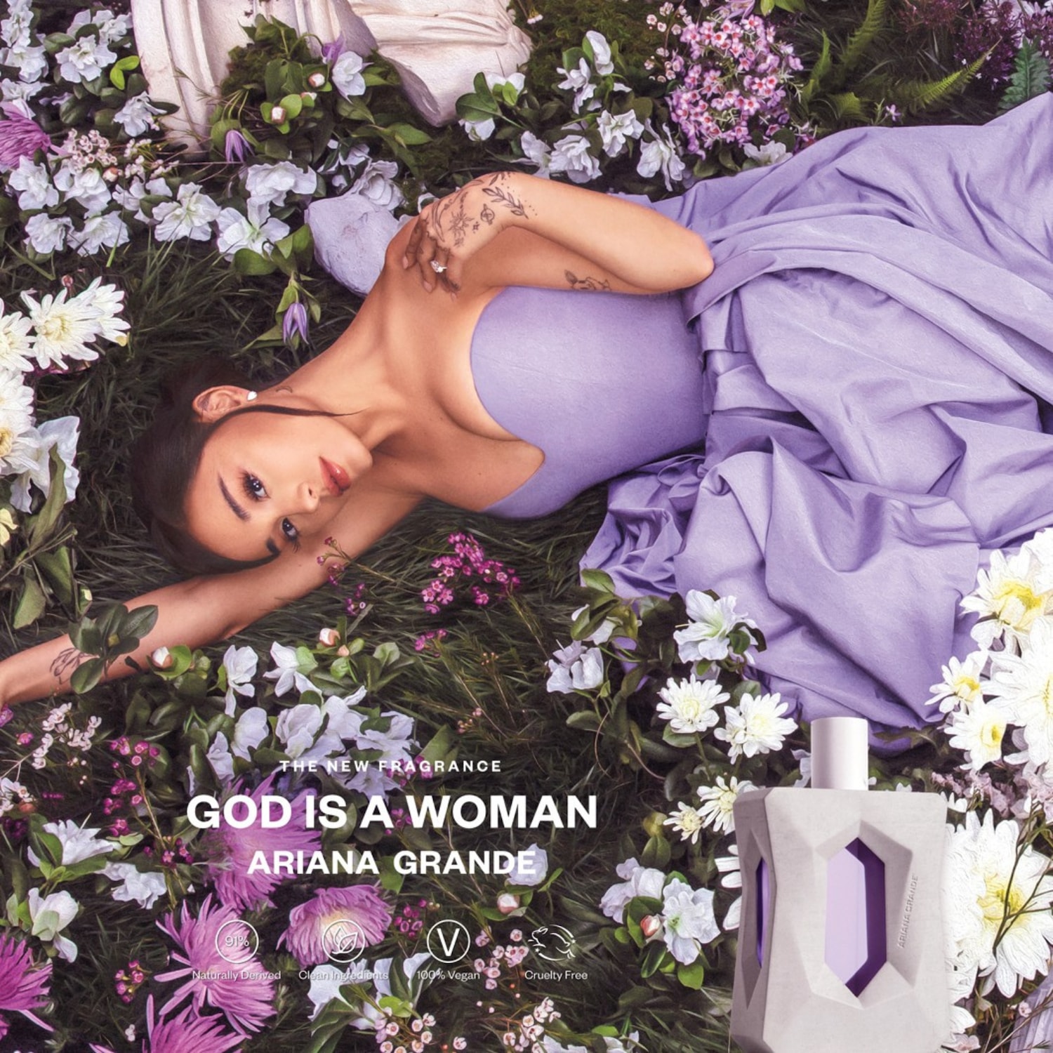 Ariana Grande ligt in een lila jurk tussen de bloemen, naast haar staat de 'God is a Woman' parfumfles, die voor 91% natuurlijk, veganistisch en dierproefvrij is.