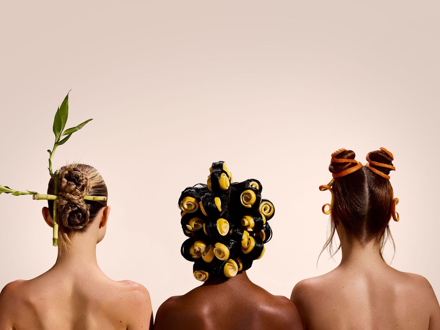 Tre donne con acconciature creative, una con bambù, una con riccioli di limone e l'altra con bucce d'arancia, che simboleggiano ingredienti naturali per la cura dei capelli.
