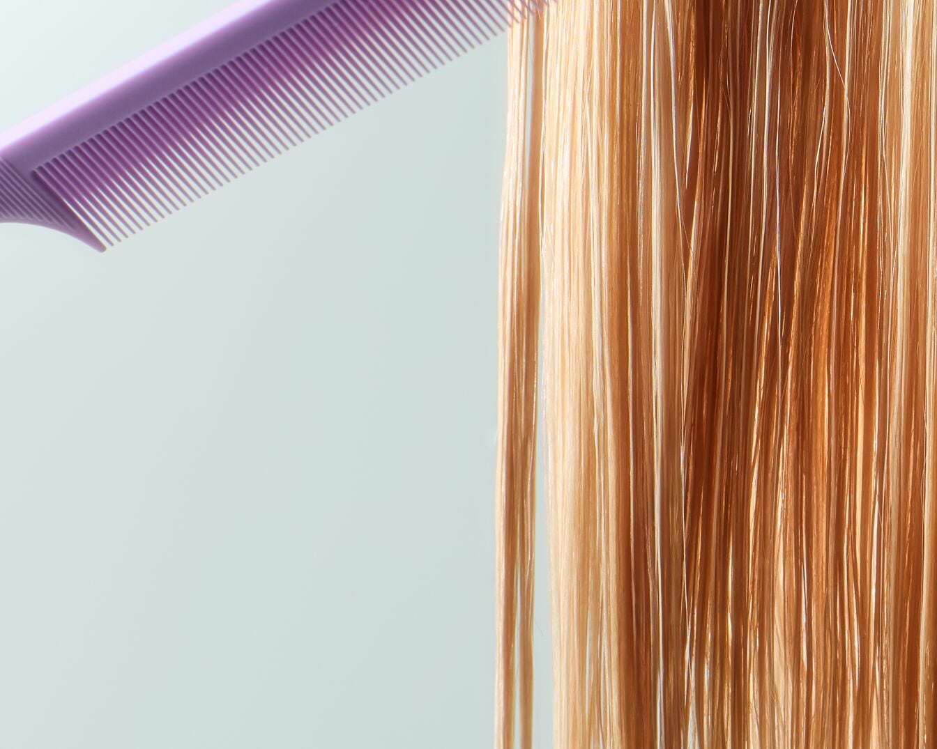 Een paarse kam glijdt door lang, blond haar, waardoor het glad en glanzend wordt.