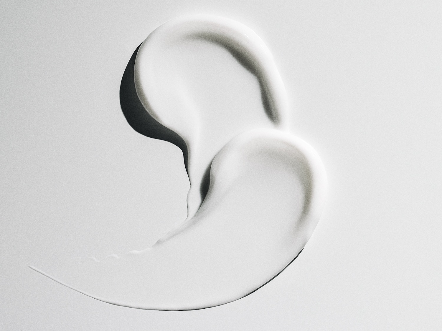 Nahaufnahme eines Klecks weißer, cremiger Lotion, die eine glatte Textur und subtile Glanzlichter aufweist.