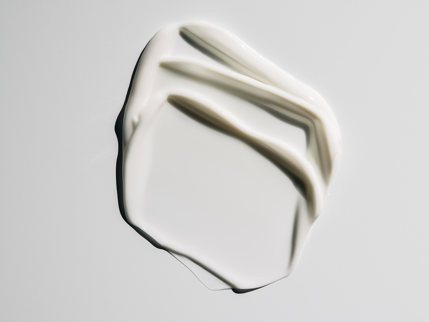 Aquí se muestra una muestra de crema blanca y brillante, extendida sobre una superficie clara, destacando su textura suave y rica.