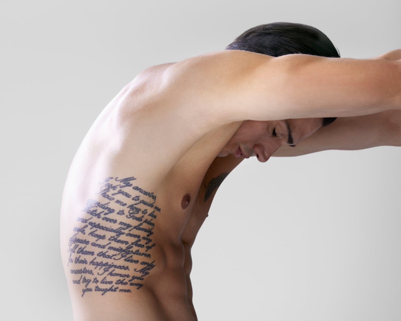Uomo a torso nudo con tatuaggio laterale che recita: "Miei antenati, vi chiedo di guidarmi, mostratemi come vivere secondo il piano di Dio, vegliate sulla mia famiglia e specialmente su mia moglie, teneteli liberi da malattie e disgrazie."