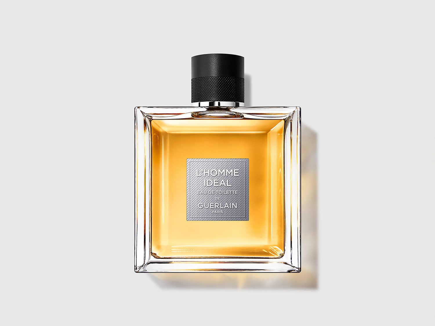 Découvrez L'Homme Idéal Eau de Toilette de Guerlain, un parfum ambré boisé pour homme dans un flacon carré élégant rempli d'un liquide doré.