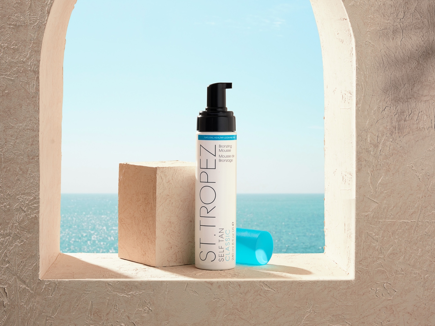 A St. Tropez önbarnító habja egy ablakpárkányon ül, a tengerre nézve, természetes, egészséges megjelenést biztosítva.