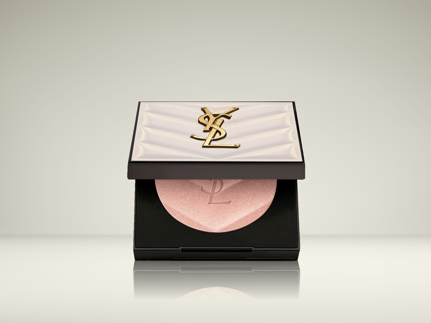 Een compacte YSL highlighter met een zwarte basis en een witte deksel met een gouden YSL logo, onthult een roze, glinsterende poeder.