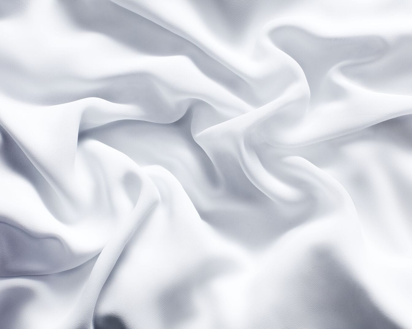 Nahaufnahme von sanft gewelltem, reinweißem Stoff, der eine ruhige und elegante Textur zeigt.