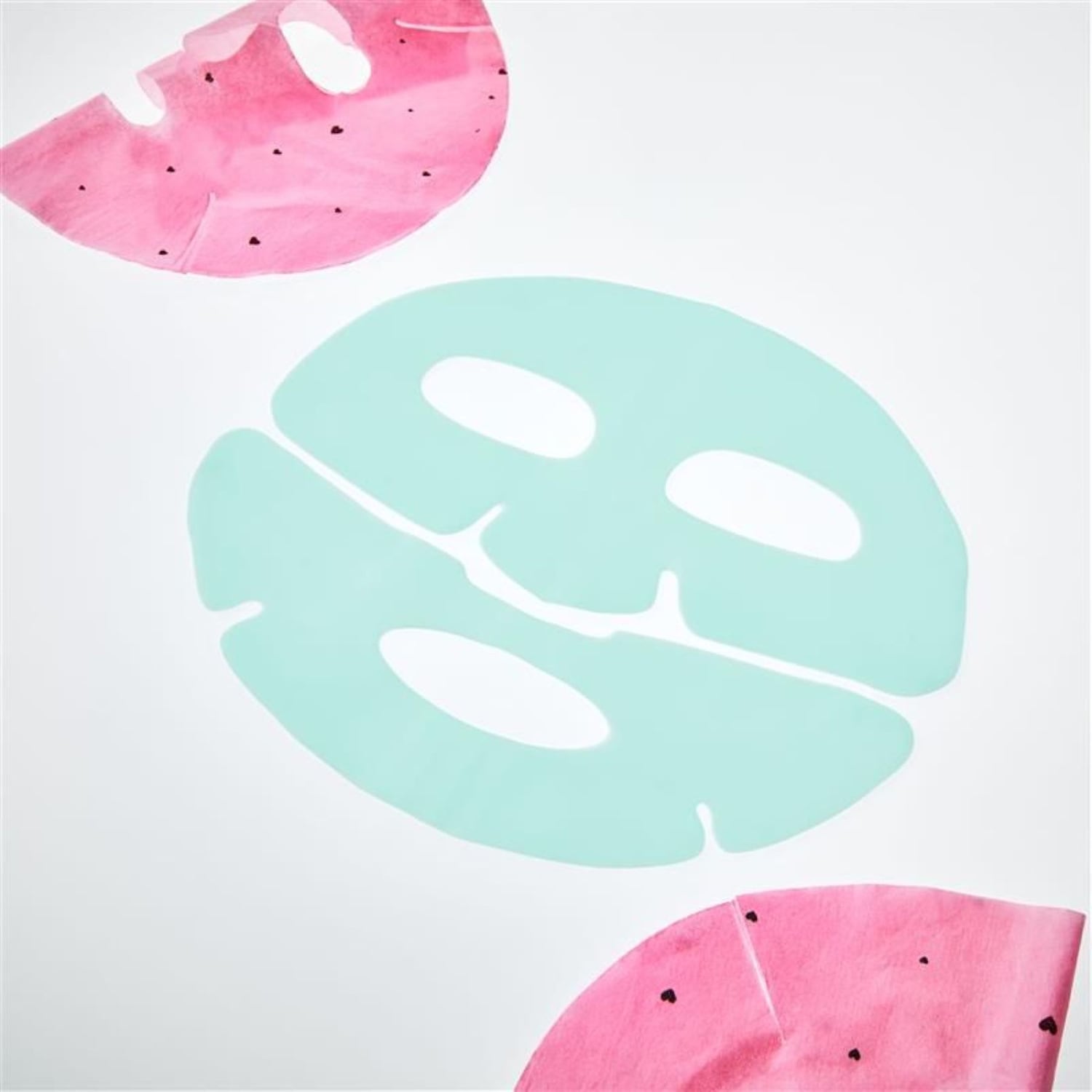 Ecco una maschera facciale verde acqua al centro e due maschere rosa anguria ai lati, perfette per una coccola di bellezza rinfrescante.