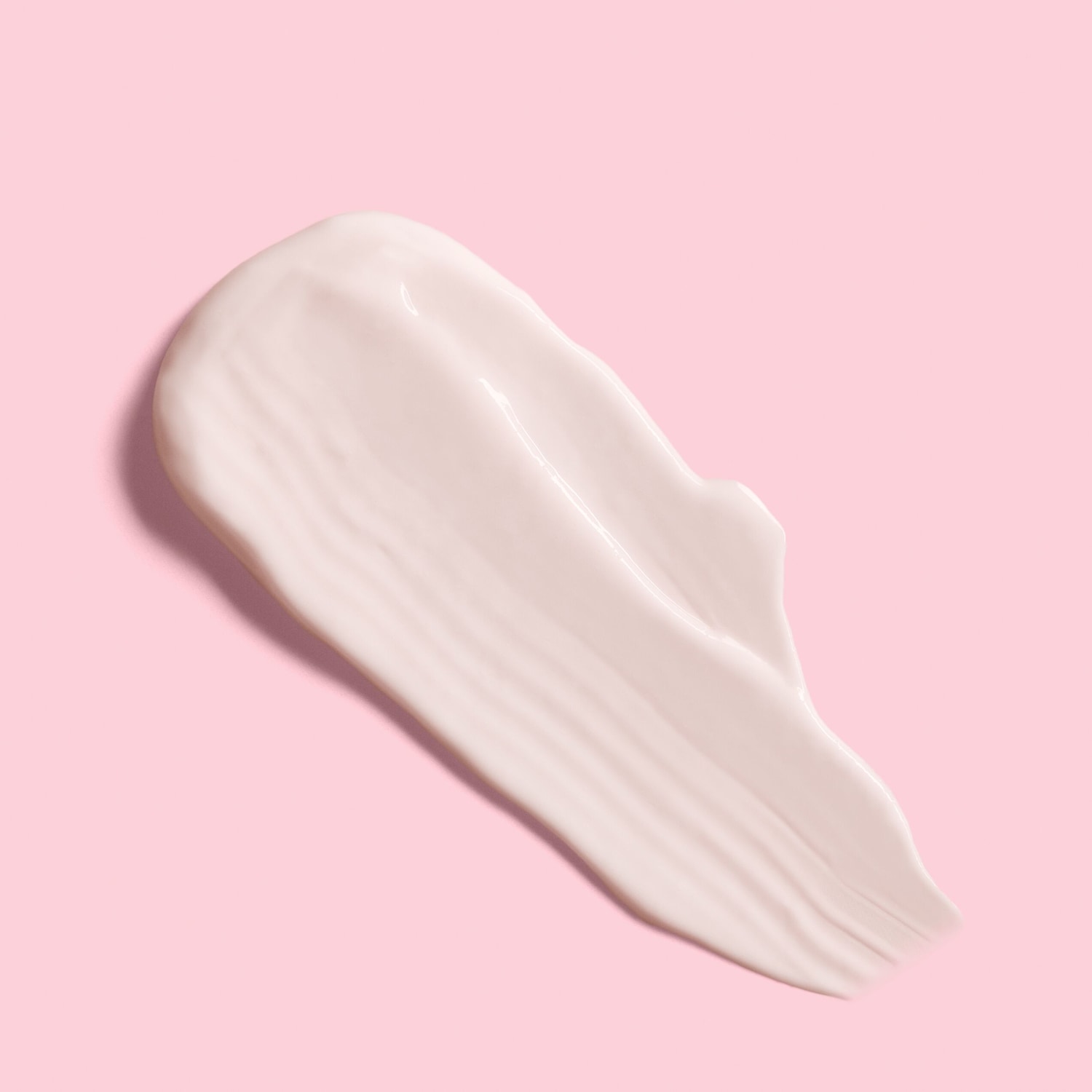 Primo piano di una striscia di crema idratante bianca e lucida su sfondo rosa.