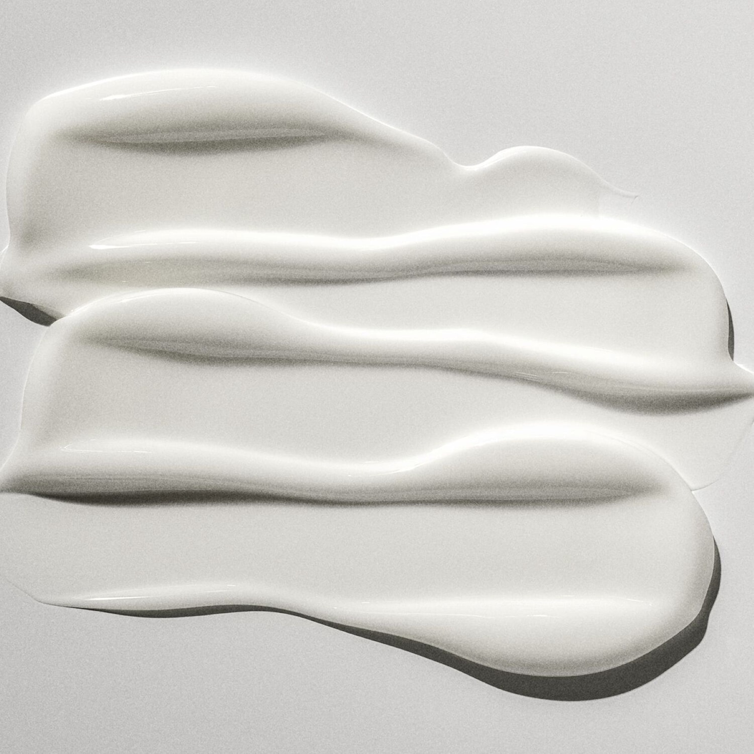 Texture cremosa e liscia di un prodotto bianco spalmato su una superficie chiara, ideale per idratare e nutrire la pelle.