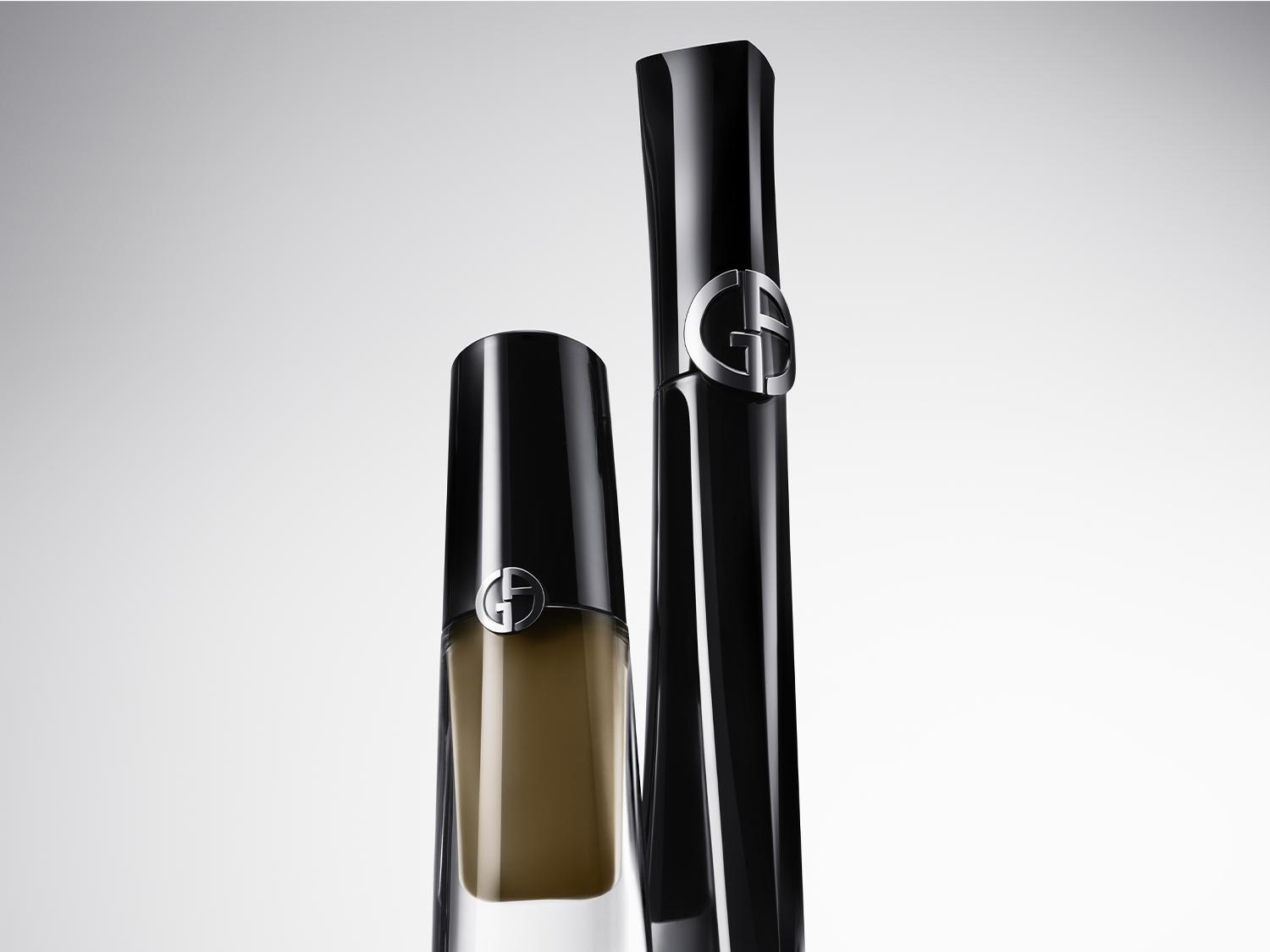 Čierny lesklý obal riasenky Giorgio Armani s logom značky a priehľadná fľaštička make-upu s čiernym vrchnákom a logom značky.