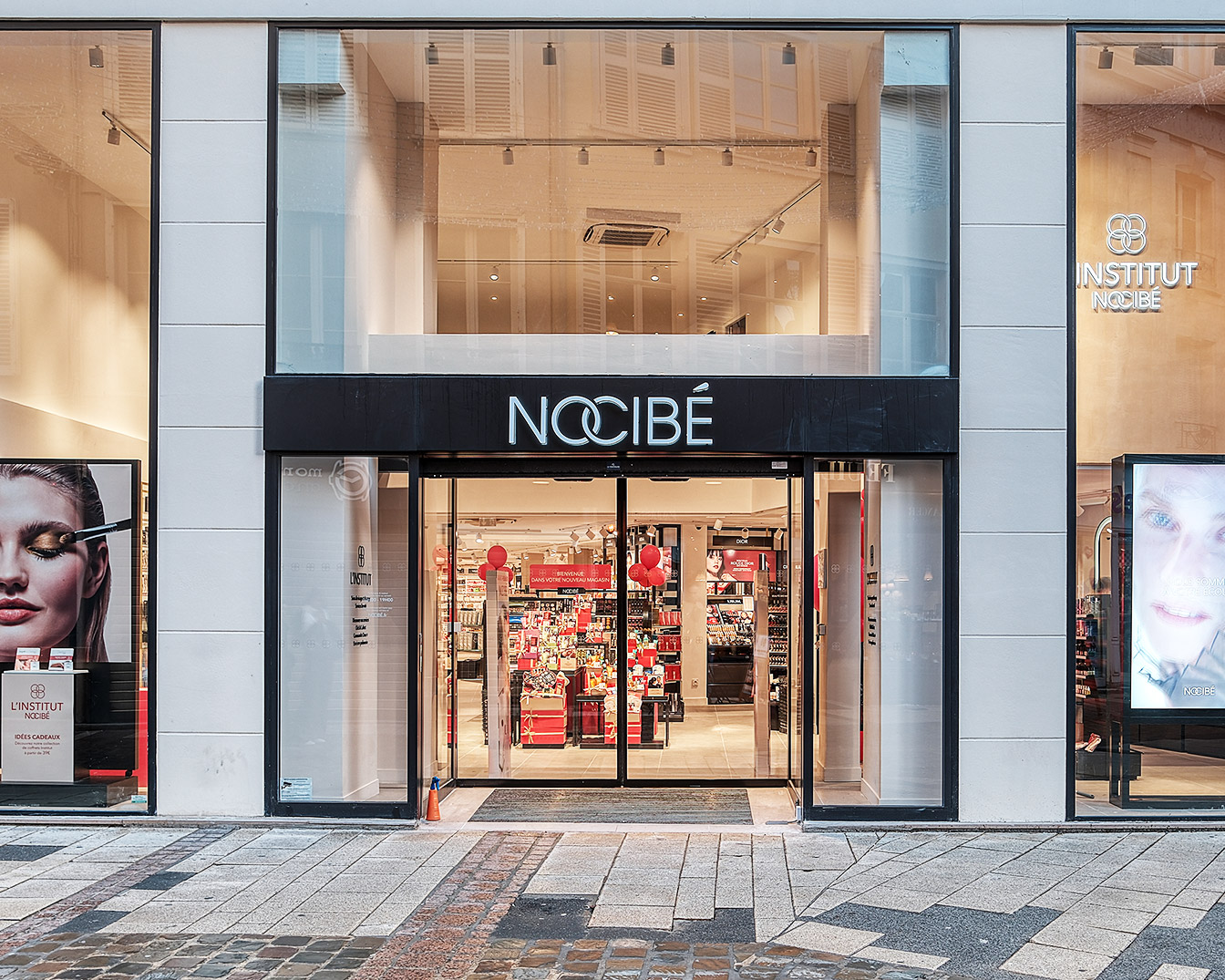 Voici la façade du magasin Nocibé avec son entrée vitrée, des affiches de produits de beauté sur les côtés et le logo bien en évidence.