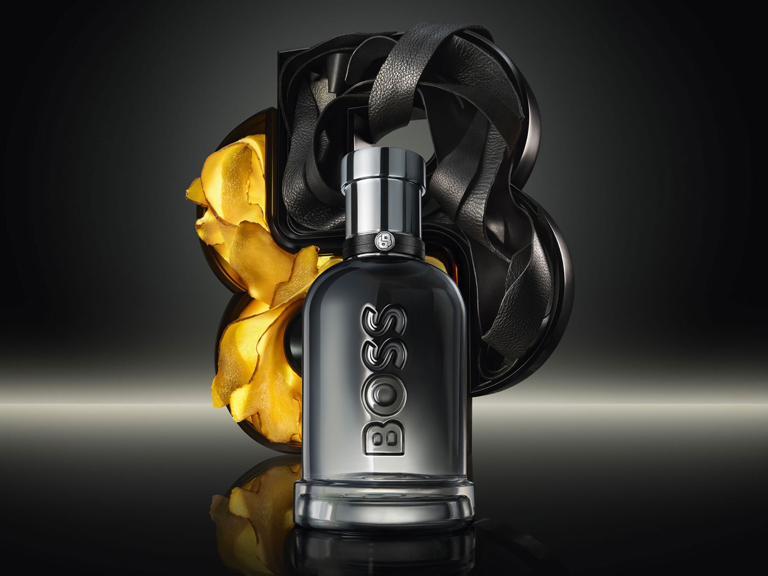 Elegantný flakón BOSS s čiernym koženým detailom a zlatistými akcentmi, stelesňujúci luxus a sofistikovanosť.